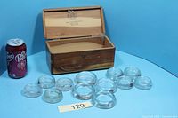 Open Lane cedar chest with twelve glass coasters displayed, soda can for scale