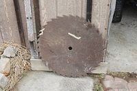 Rusted 24-inch circular saw blade leaning against wooden wall