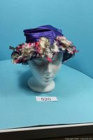 Front view of purple satin hat with flower trim