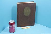 Front cover of yearbook beside soda can for scale