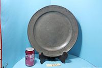 Front view of pewter charger with reference can for scale