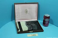 Open presentation case showing six knives and six forks with cream handles; Dr Pepper can for scale