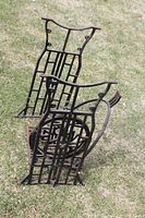 Two vintage cast iron sewing machine base frames standing on grass