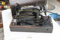 Front/side view of Singer sewing machine in wooden base with cover behind