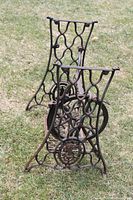 Full view of disassembled Singer cast iron base pieces standing upright on grass