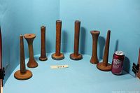 Group shot of seven wooden bobbins with soda can for scale