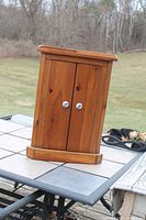 front view of wooden corner cabinet with doors closed showing ceramic knobs