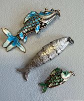 Three articulated fish pendants showing enamel colors and segment detail