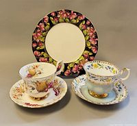 Overall lot showing two teacup and saucer sets with floral designs plus floral rim plate