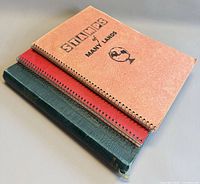 Stack of three stamp albums showing covers and binding.