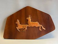 Front of wooden plaque showing two copper antelopes relief