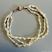 Full view of triple-strand freshwater pearl bracelet laid flat
