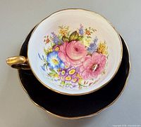 Teacup resting on saucer showing floral interior and black exterior