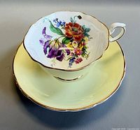 Teacup on saucer, showing floral interior and yellow exterior
