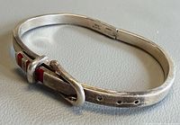 Overall view of sterling silver buckle bangle showing red enamel stripes and adjustment holes