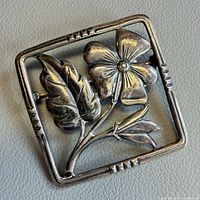 Front view of sterling silver brooch showing flower and leaf design
