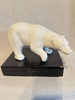 Left side view of glazed white ceramic polar bear figurine on display box