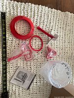 All components spread out: red lid, handle, rings, clear bowl, accessories, manual