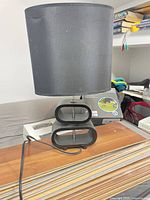 Front view of black table lamp showing fabric shade and oval-cutout base