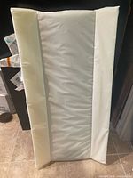 Front view of contoured change table pad showing grey centre sleep surface and white side bolsters