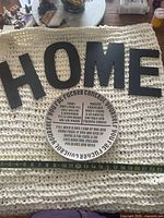 Overall view of four HOME letters and humor plate on knitted surface with measuring tape