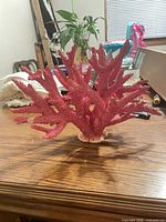 Front view of pink faux coral ornament on wood table