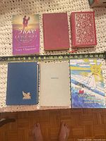 Front covers of six books with measuring tape for scale