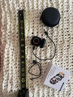All contents laid out with measuring tape for scale: ring, charging cradle with cable attached, USB cable, zip case, product box