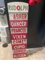 front of wooden sign showing reindeer names