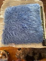 Top view of one blue faux-fur pillow with tape measure for size reference