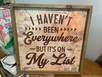 Front view of wood-framed wall sign with travel quote