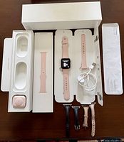 Complete lot laid out with Apple Watch, sport band pieces, charging cable, extra leather bands, original box