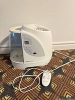 Humidifier front view with water tank, display, remote control and power cord