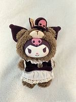 Front view of brown Kuromi plush wearing purple hood and dress