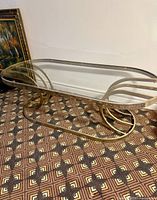 Angled view of entire coffee table showing glass top and brass-tone base