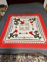 Full view of square tablecloth laid flat showing entire design and red border