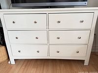 Front view of white six-drawer dresser with metal knobs