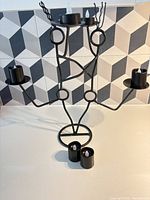Full view of black metal 6-arm abstract candelabra with two LED tealights inserted and two additional adapters in front