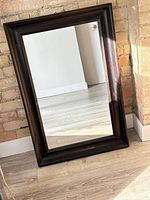 Full view of rectangular mirror leaning against wall