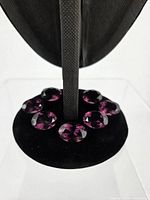 Seven oval amethyst stones displayed on black velvet pad