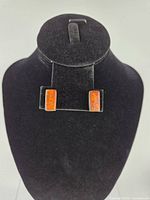 Frontal view of both rectangular amber sterling silver earrings on display stand