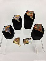 Overview of all six enamel brooches on stands and riser