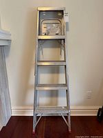 Front view of the 5-foot aluminum step ladder showing four steps, top tray and red feet