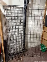 Two stacks of metal grid panels leaning against wall