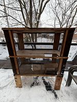 Full view of the wooden two-floor mesh pet enclosure standing on snow
