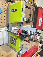 Full view of Ryobi band saw on bench showing table, fence, knobs, brand label