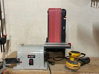 Porter-Cable bench belt sander beside DeWalt palm sander on workbench