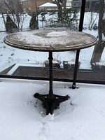 Full view of round stone-top bistro table on balcony in snow
