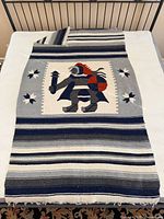 Full blanket laid flat showing stripes, central motif, fringe