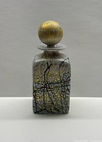 Front view of square perfume bottle showing Golden Rain design and stopper in place